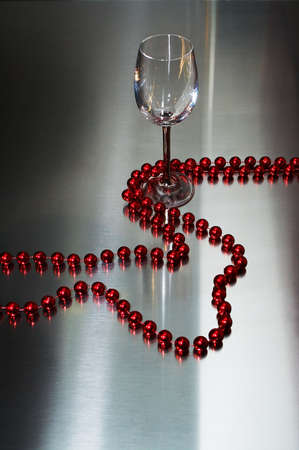 Wine-glass and red beads on a metal backgroundの写真素材