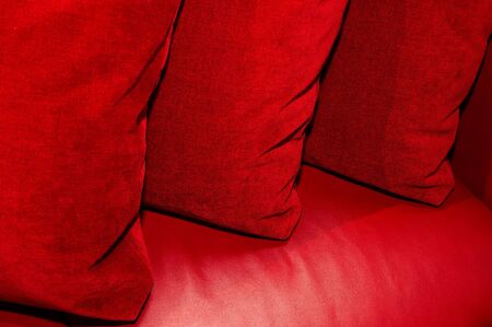 Three red pillows on a leather sofaの写真素材