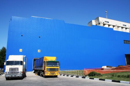 Two lorries on a background of a dark blue warehouseの写真素材