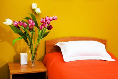 Beautiful tulips at a bed with an orange coverletの写真素材