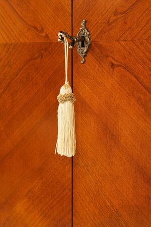 Bronze key with a tassel in a keyholeの写真素材