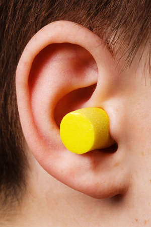yellow earplug into the ear close upの写真素材