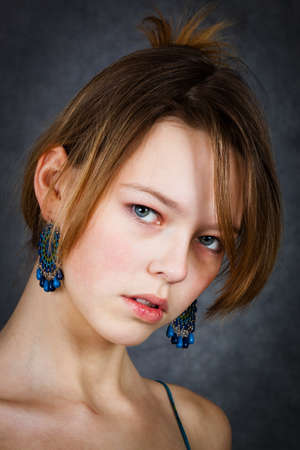 girl with blue earrings on a gray backgroundの写真素材