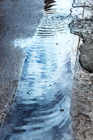 rain stream on the pavement in the cityの写真素材
