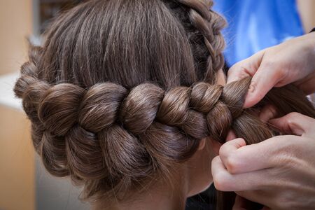 weaving braids brunette in a hairdressing salonの写真素材