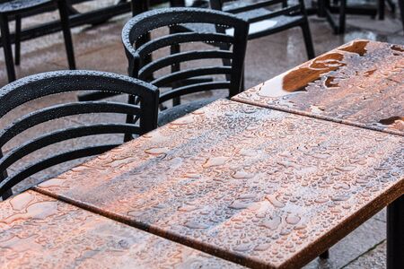 outdoor wet wooden tables and chairs under the rain