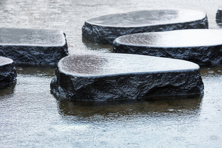 wet stones in the rain in the pondの写真素材