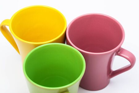 yellow, green and pink coffee cups on a white backgroundの写真素材