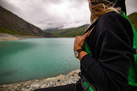 Woman taking break after sports training. She is standing with her hands on hips looking to the clear lake at cloudy day. Female athlete in wearing a watch.の写真素材