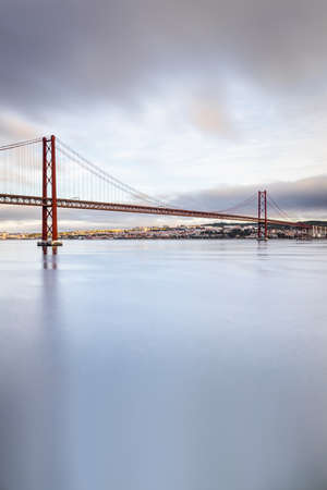 the 25 de Abril suspension bridge over Tagus river in Lisbon, Portugal at sunriseの写真素材