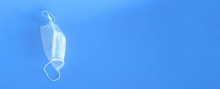 Wide banner with the image of a protective medical mask close-up on a blue background. There is...