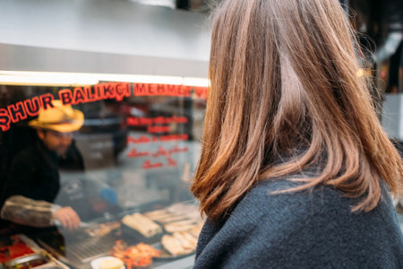 TURKEY, ISTANBUL, DECEMBER 14, 2018: Girl watching street food cookingのeditorial素材
