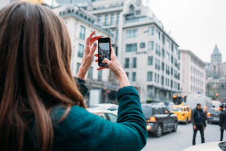 TURKEY, ISTANBUL, DECEMBER 14, 2018: Beautiful girl in a coat takes pictures of sights on smartphoneのeditorial素材
