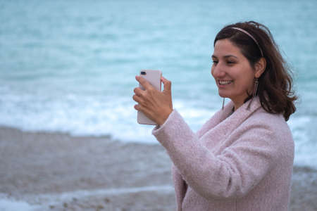 Girl blogger communicates with the audience on a smartphone near the sea close-up