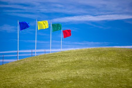 Four colorful flags on green grassy hill invite shoppers to attend an open house or other sales event.  Ample room for copy.の写真素材