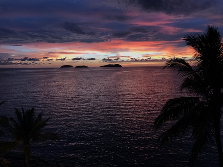 Sunset view during dusk with colorful sky and clouds overlooking horizon and sea with silhouette of islands and palm trees at the beach in tropical paradise Sabah, Malaysia.の写真素材