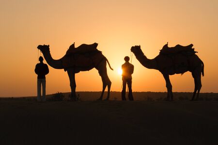 JAISALMER, INDIA - NOVEMBER 15,2008: Silhouette of unidentified local people and camels at sunset on November 15,2008 in Thar desert near Jaisalmer, Rajasthan, India.のeditorial素材