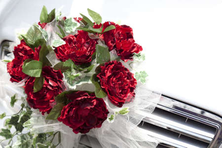 Closeup of a brides red rose bridal bouquet in front of carの写真素材