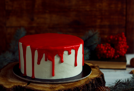 Homemade Christmas red cake on a rustic wood stand and festive decoration. Red tasty ganacheの写真素材