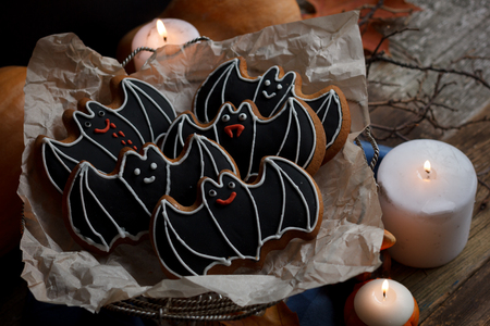 Halloween bats sugar cookies with decorations, candles light and wooden old backgroundの写真素材