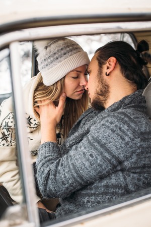 Handsome hipster Man and beauty woman kiss each other sitting in the retro car . Valintines Day concept. Vertical pictureの写真素材