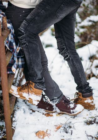 legs of the young girl stand opposite to legs of the young man, lovers. Snow background. Fashion shoes and dark grey jeansの写真素材