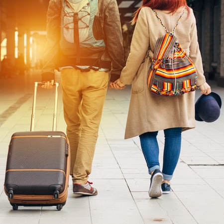 Legs Loving Couple happy hugging in the train station of a country after arrival in autumn with a warm sunlight background. Trolley broun bag. Travel conceptの写真素材
