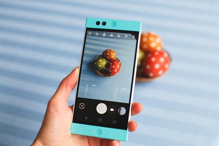 easter, holidays, tradition, technology and people concept - close up of woman hands with smartphone taking picture of colored easter eggsの写真素材