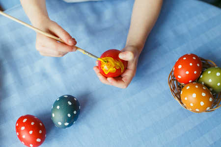 Happy easter. Cute little child painting with bright colors Easter eggs. family preparing for Easter. Hands of a kid with an easter egg.の写真素材