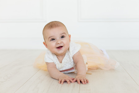 Little fairy. sweet ballerina with fluffy peach skirt and flower. Cute smiling baby girl on white studio backgroung. 6 months babyの写真素材