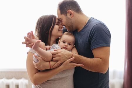 Baby with his parents playing on the bed. Happy family at home. Lifestyle cozy photos. Little boy 4 months oldの写真素材
