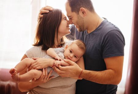 Baby with his parents playing on the bed. Happy family at home. Lifestyle cozy photos. Little boy 4 months oldの写真素材