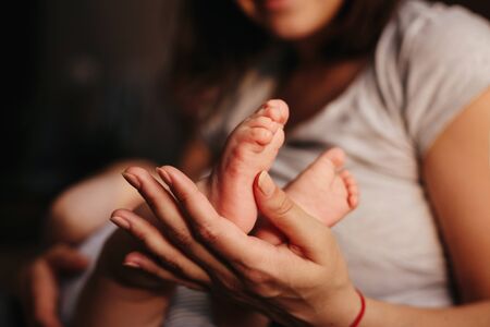 Baby feet in mother hands. Tiny Newborn Babys feet on female Shaped hands closeup. Mom and her Child. Happy Family concept. Beautiful conceptual image of Maternityの写真素材