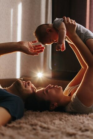 Baby with his parents playing on the bed. Happy family at home. Lifestyle cozy photos. Little boy 4...