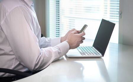 Businessman typing and writing with smartphone in office to home or co-workers. Man texting or...