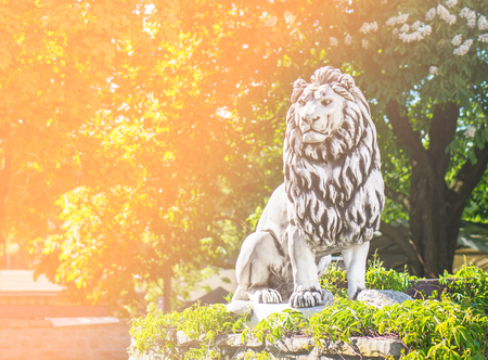 Lion statue standing in forest and nature. Perfect background template for motivation, courage and determination related quote or text. Success concept with orange fade filter and copy space.の写真素材
