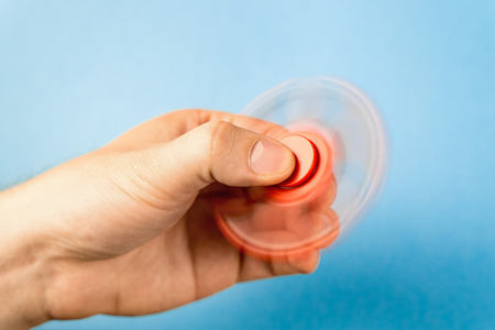 Fidget spinner spinning in hand with blue background.の写真素材