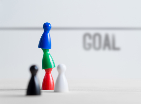 Teamwork, reaching goals, working together and success concept. Colorful board game pawns on each other. Cooperation, leadership, achievement and support.の写真素材