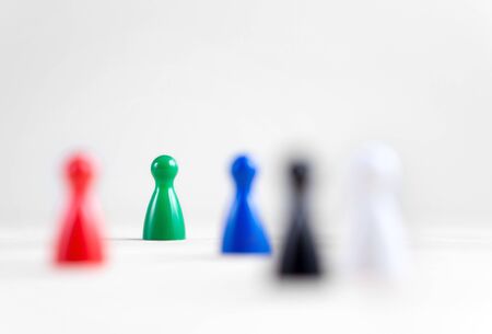 Many board game pawns on table, selective focus on the green one. Being brave, be yourself and originality concept. Diversity and tolerance.の写真素材