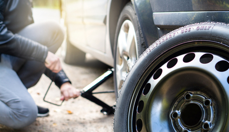 Driver changing spare tyre after accident. Broken and flat car wheel after crash. Man fixing problem...