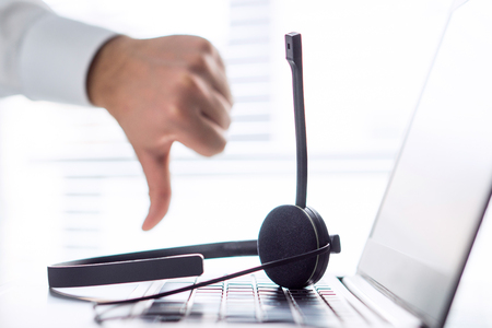 Unhappy help desk, support hotline or call center person showing thumbs down. Tele marketing professional having horrible day, not satisfied. Bad feedback or working conditions.の写真素材