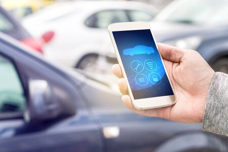 Internet of things (IOT) mobile app in smart phone for modern car. Hand holding smartphone...