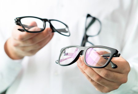 Optician comparing lenses or showing customer different options in spectacles. Eye doctor showing new glasses. Professional optometrist in white coat with many eyeglasses.の写真素材