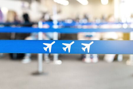 Airport waiting area, lobby or lounge. Airplane icon in queue barrier. Passengers sitting in the background. Travel and vacation concept.の写真素材