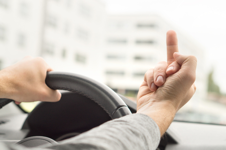Road rage. Man driving and showing middle finger in car. Driver flipping the bird. Bad behavior and attitude in traffic.の写真素材