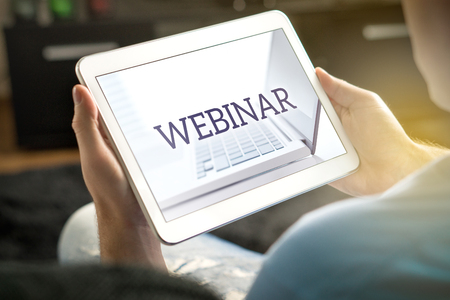 Webinar on tablet screen. Man holding smart mobile device and participating in a web seminar.の写真素材