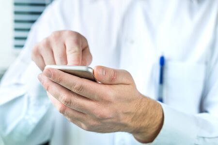 Doctor using mobile phone. Person in white coat typing smartphone.の写真素材