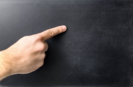 Teacher pointing empty blackboard. Hand and finger on a blank chalkboard. Negative copy space.の写真素材