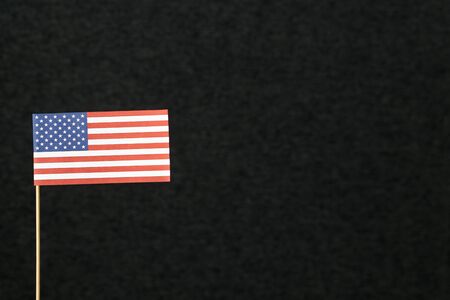 The flag of United States of America (USA) made from paper on wooden stick against dark background with negative copy space for text.の写真素材
