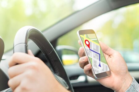 Man driving car and using online map and GPS application on with smart phone. Navigation with mobile app. Inside view in car to hand holding smartphone.の写真素材